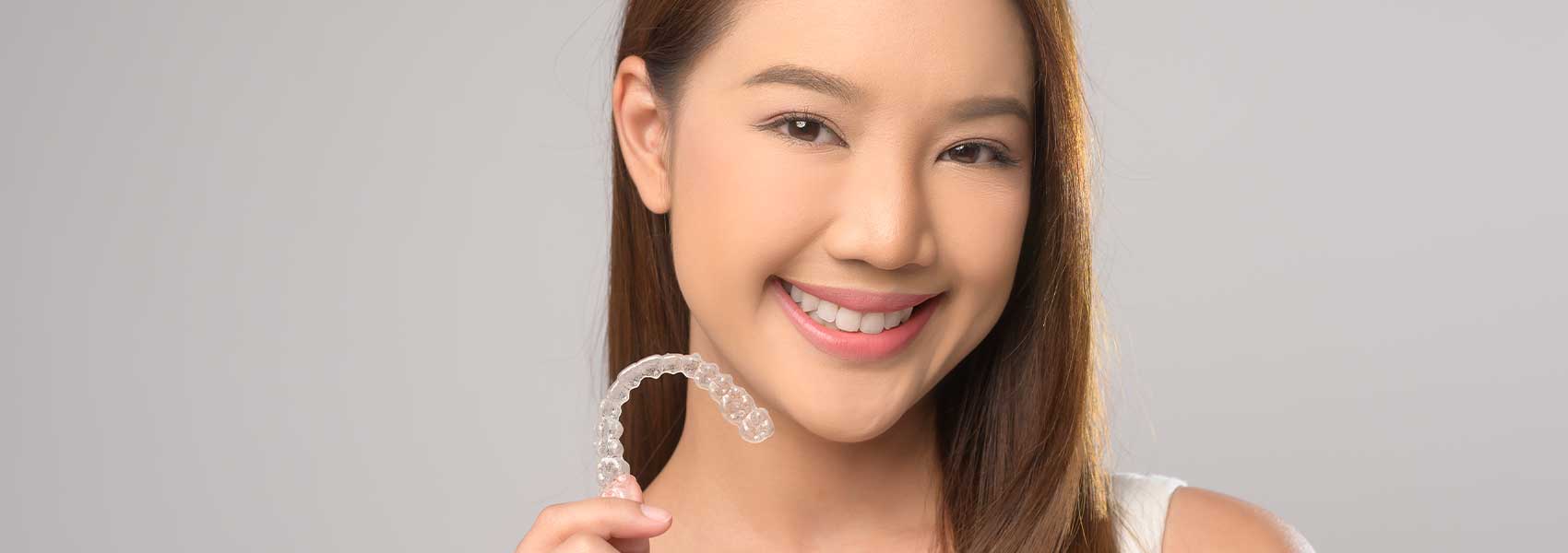 Beautiful girl is smiling and holding a Invisalign