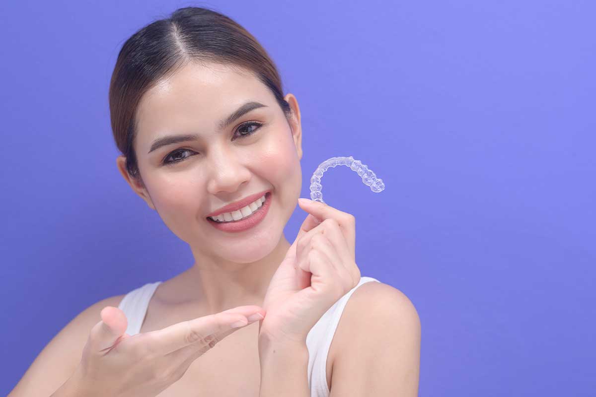 Beautiful woman smiling and holding a Invisalign