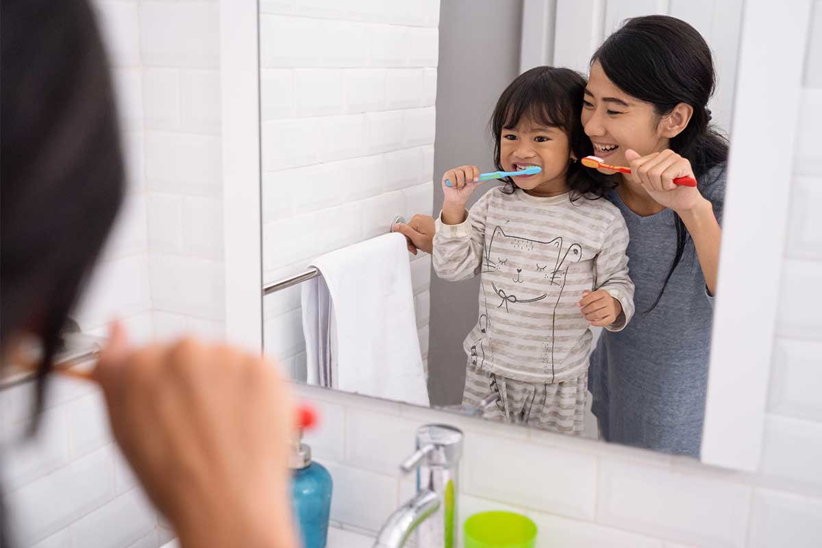 Mother and daughter brushing teeth in the bathroom sink