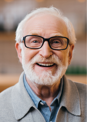 Smiling senior man with glasses, representing trusted dental care for implant patients.