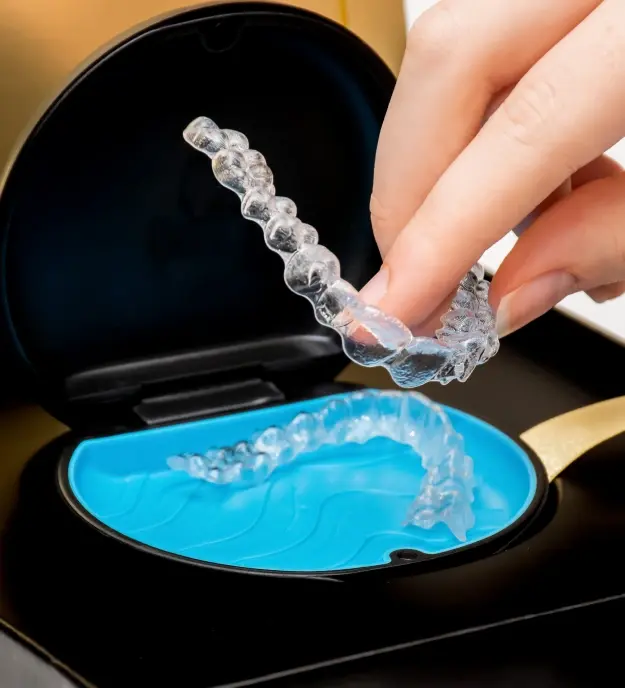 Hand holding clear Invisalign aligner over blue storage case in Orlando dental office.