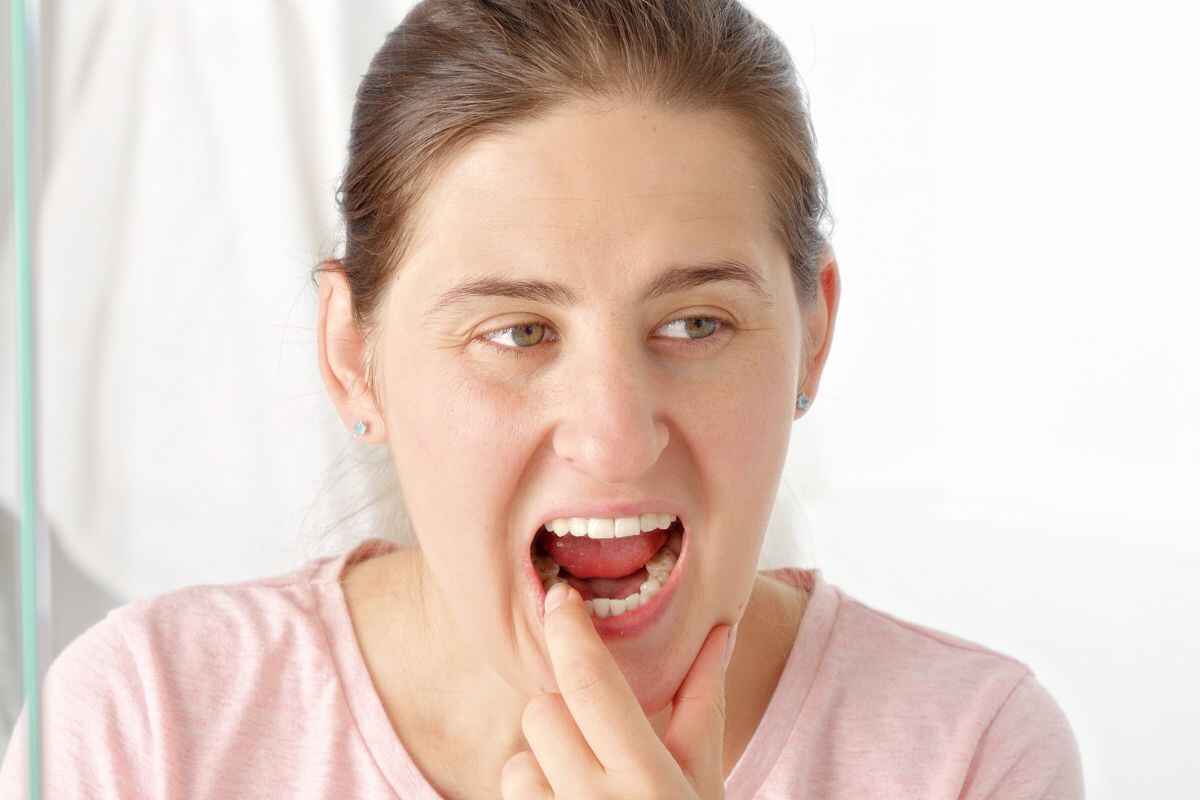 Woman touching her cheek in pain, experiencing tooth discomfort related to intermittent dental issues.