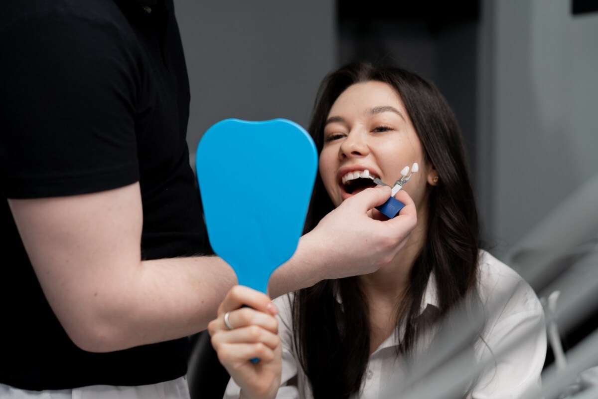 Dentist showing dental veneer shade guide to smiling patient during consultation in Orlando.