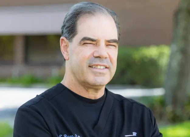 Dr. John Russo, dentist at Orlando dental practice, smiling outdoors.