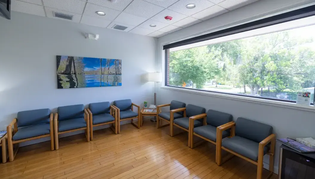 Modern dental office waiting area with comfortable seating and large windows overlooking trees in Orlando.