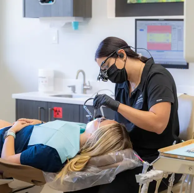 Dental hygienist performing tooth extraction procedure on patient in Orlando treatment room.