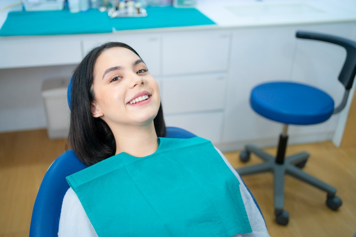 Happy patient wearing dental bib in treatment room, smiling after cosmetic dental procedure.
